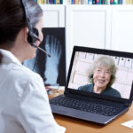 Practitioner with headset conducting a Telehealth appointment on a laptop.